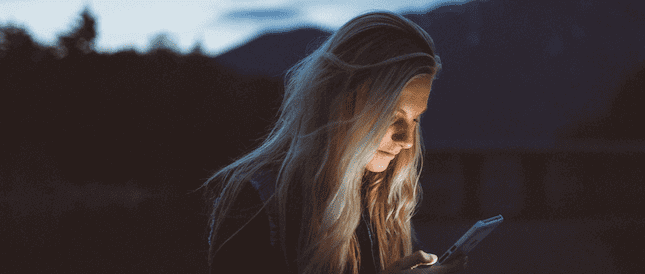 Woman smiling and reading her phone text messages. 